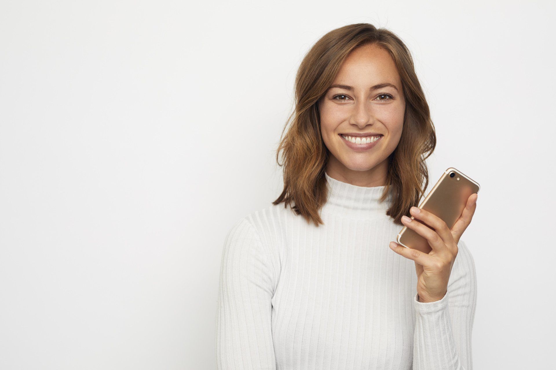 Eine Frau lächelt und hält ein Mobiltelefon in der Hand.