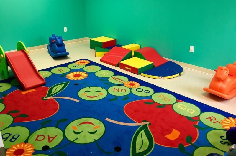 A room with a blue wall and a rug with apples on it