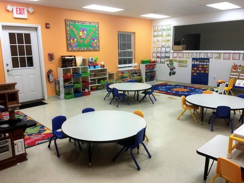 A classroom with tables and chairs and an exit sign