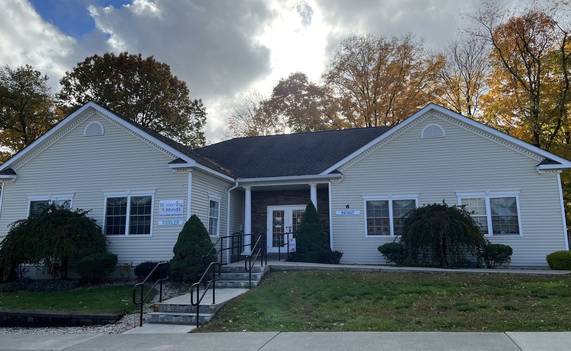 A white house with a black roof is surrounded by trees