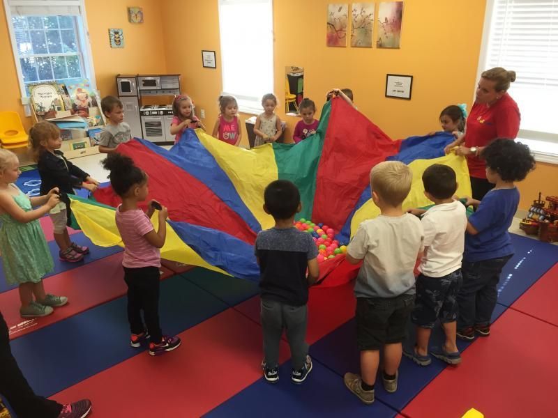 A group of children are playing with a colorful parachute