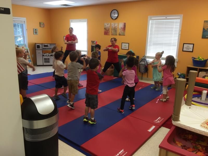 A group of children are standing on mats in a room