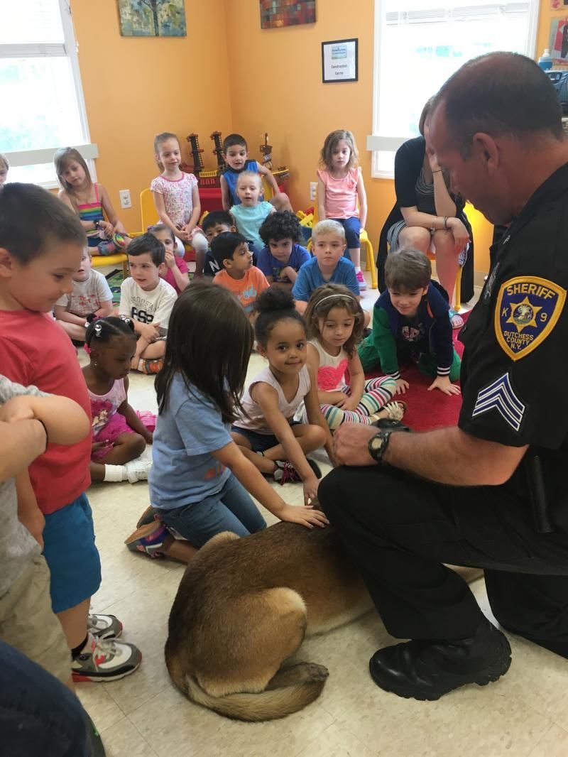 A police officer petting a dog in front of a group of children