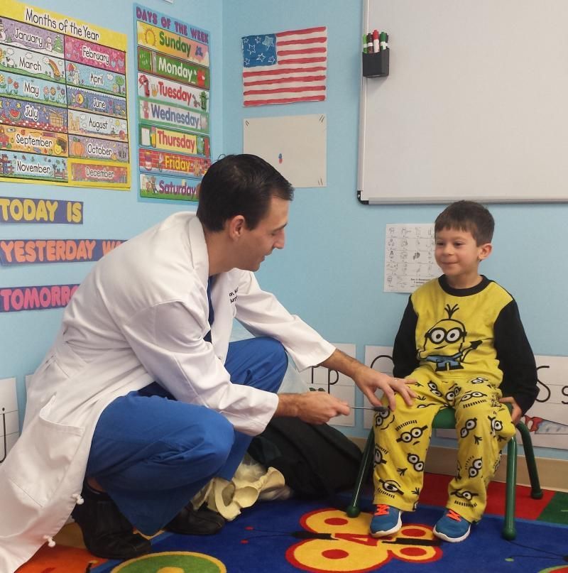 A man in a lab coat is kneeling down next to a child in a yellow minion outfit