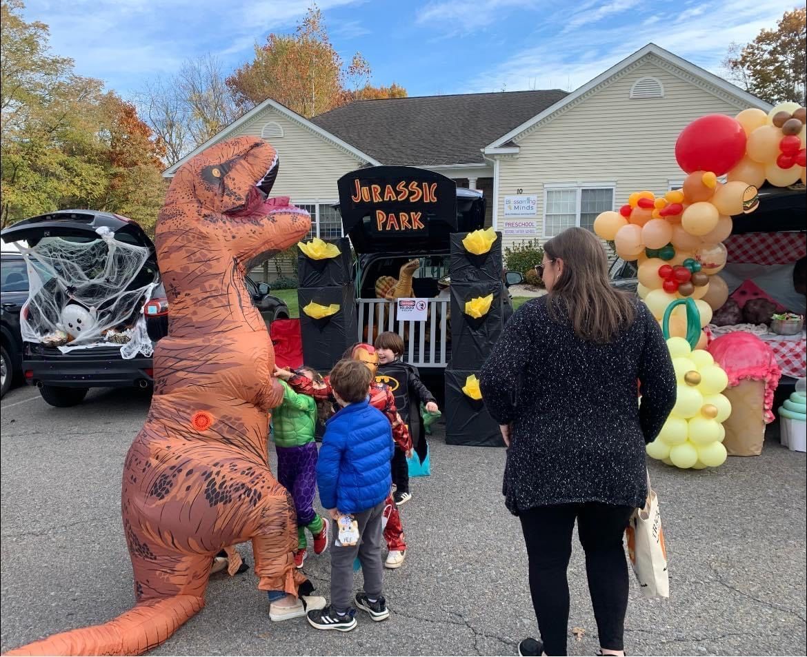 A group of children are standing in front of a t-rex costume.