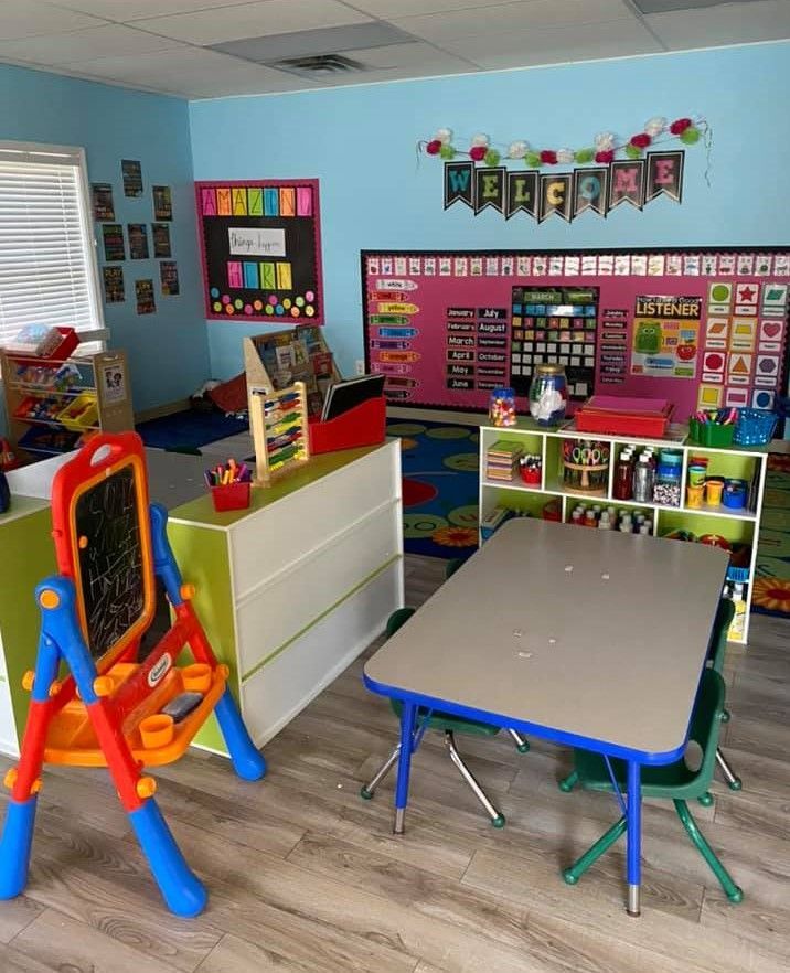 A classroom with a table and chairs and a chalkboard