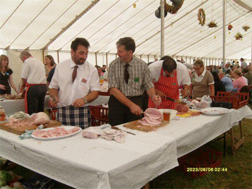 A group of people are standing around a table with food on it.