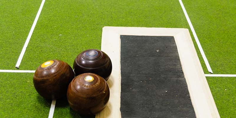 Three bowling balls are sitting on top of a green field.