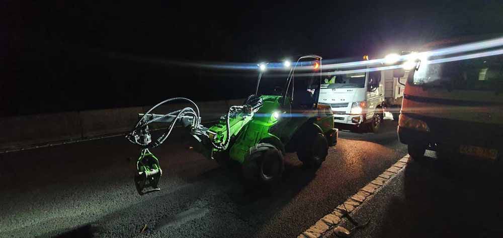 A Green Tractor Is Parked on The Side of The Road at Night — Burnett Trees in Kiama, NSW