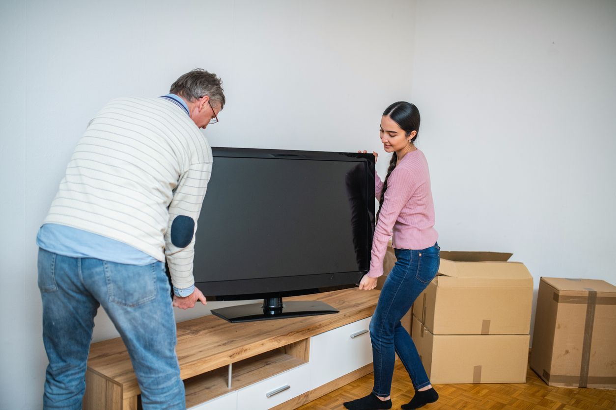 A father and daughter trying to pack a flat-screen tv for a move