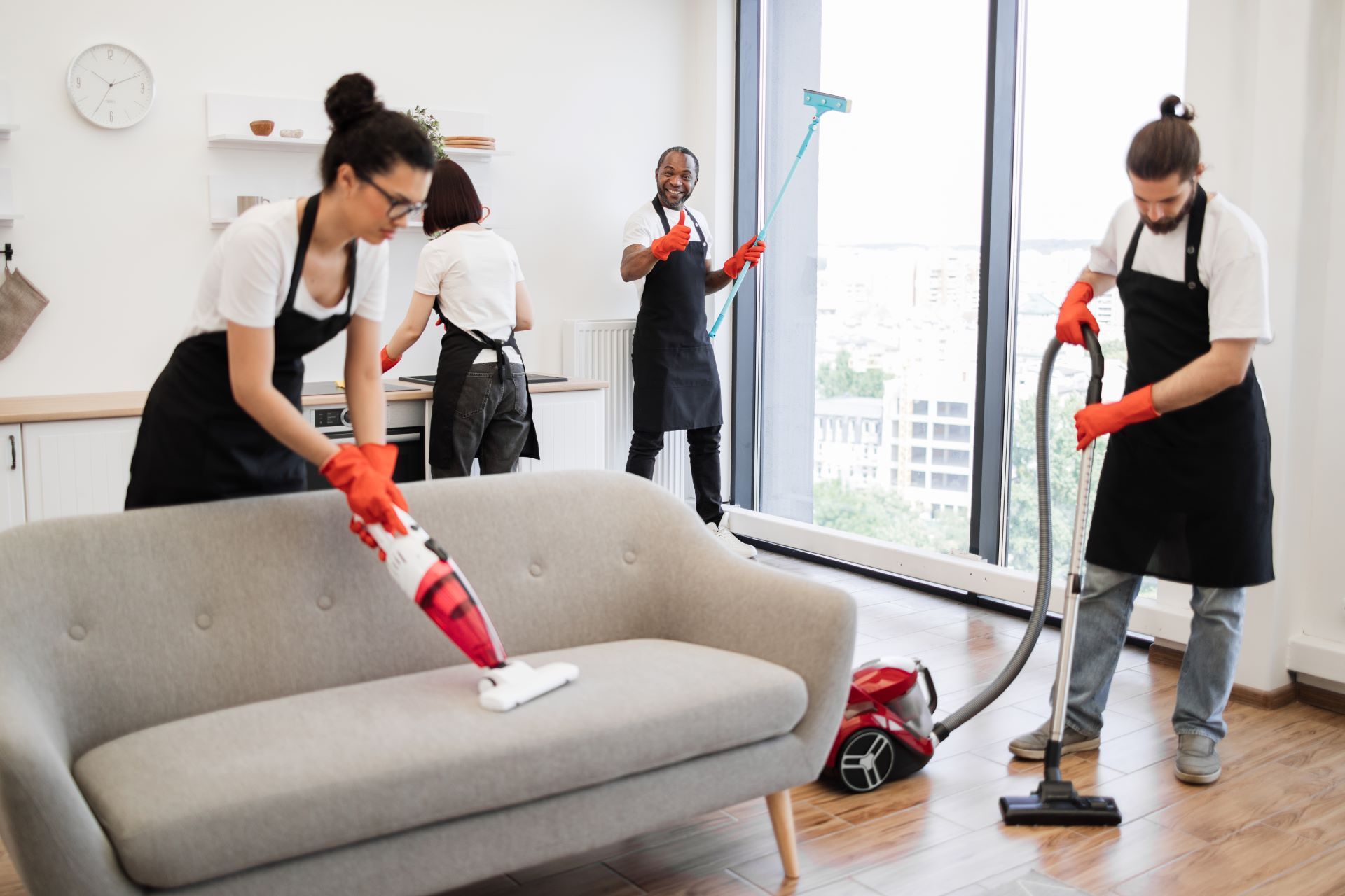 A group of people are cleaning a living room with a vacuum cleaner.