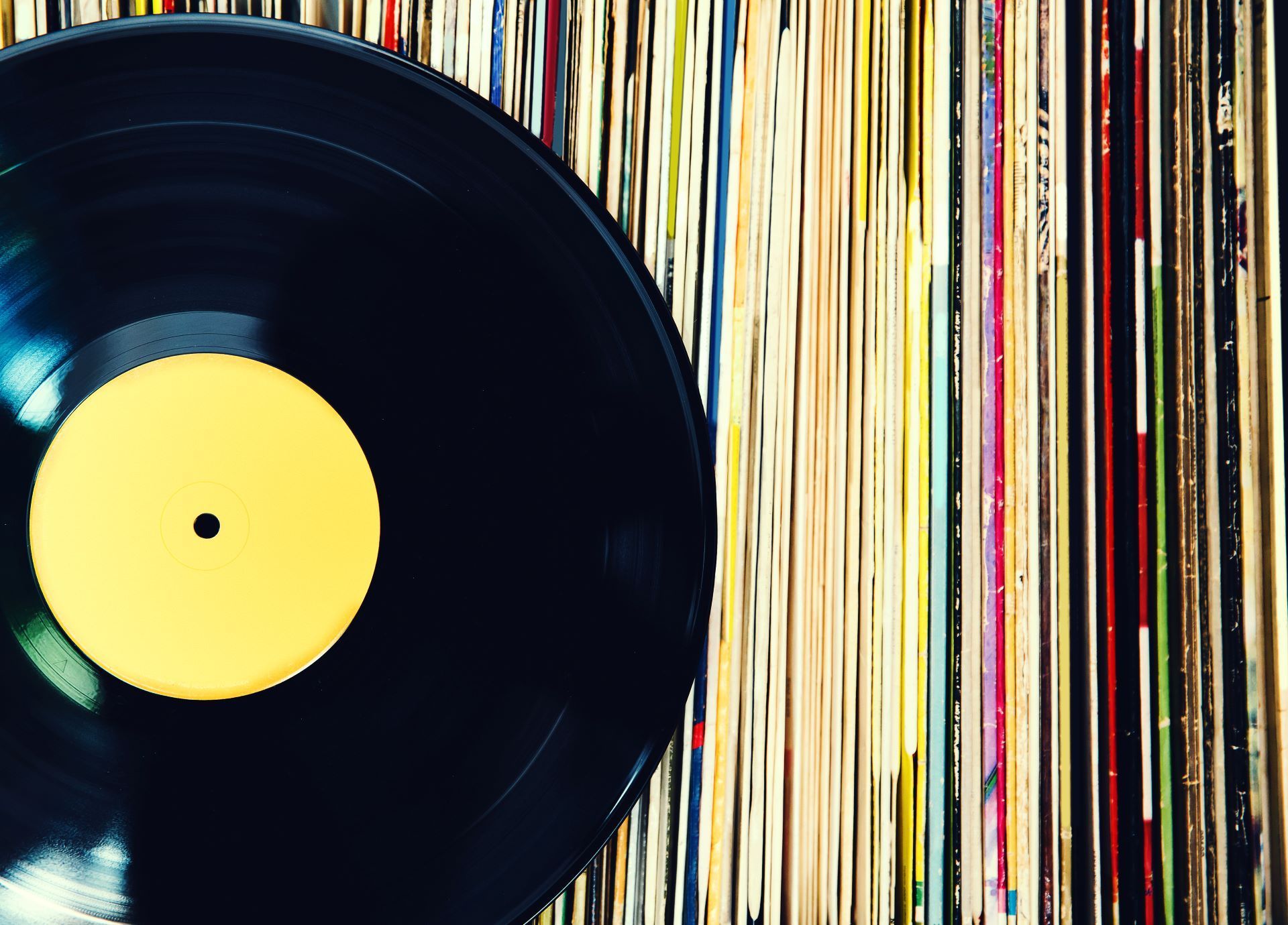 close up photo of a vinyl record leaning on a row of records still in sleeves
