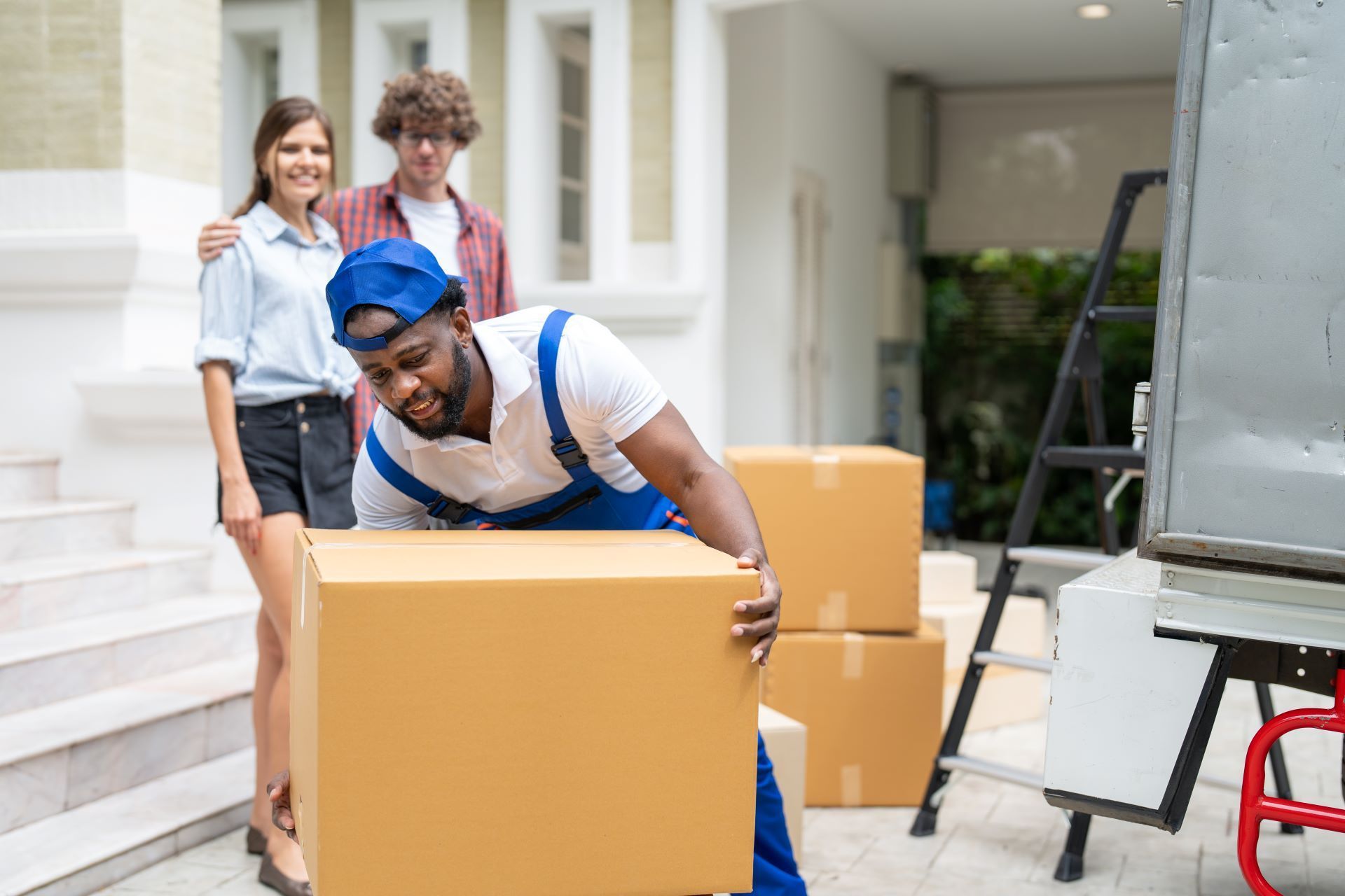 A man is lifting a cardboard box in front of a house.