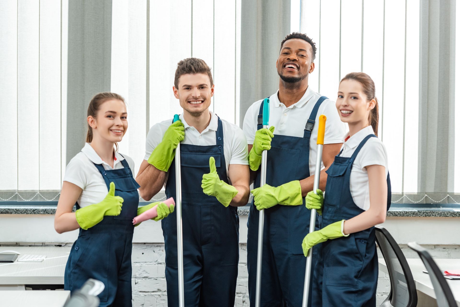 A group of cleaners are posing for a picture and giving a thumbs up.