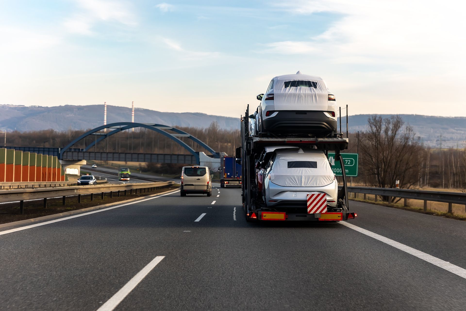 A truck is carrying cars on a highway.