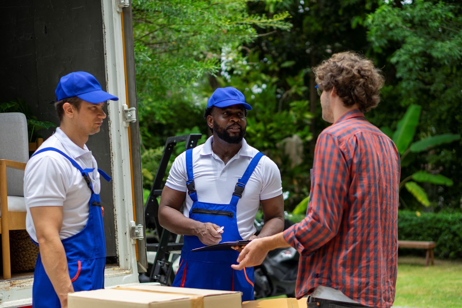 A group of men are standing next to each other in front of a moving truck.