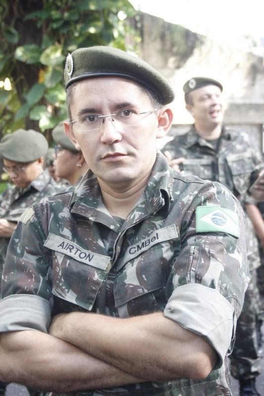 Homem em uniforme militar brasileiro com os braços cruzados e usando uma boina verde.
