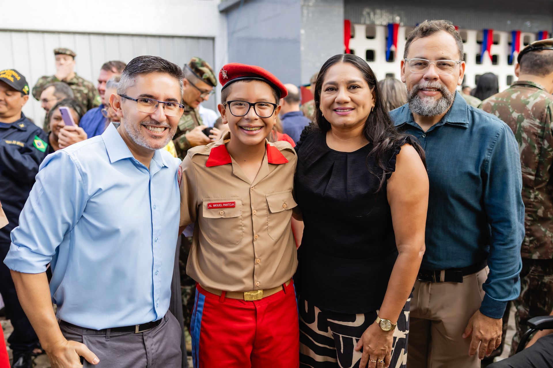 Família com um jovem em uniforme de cadete. Eles sorriem em um ambiente de cerimônia.