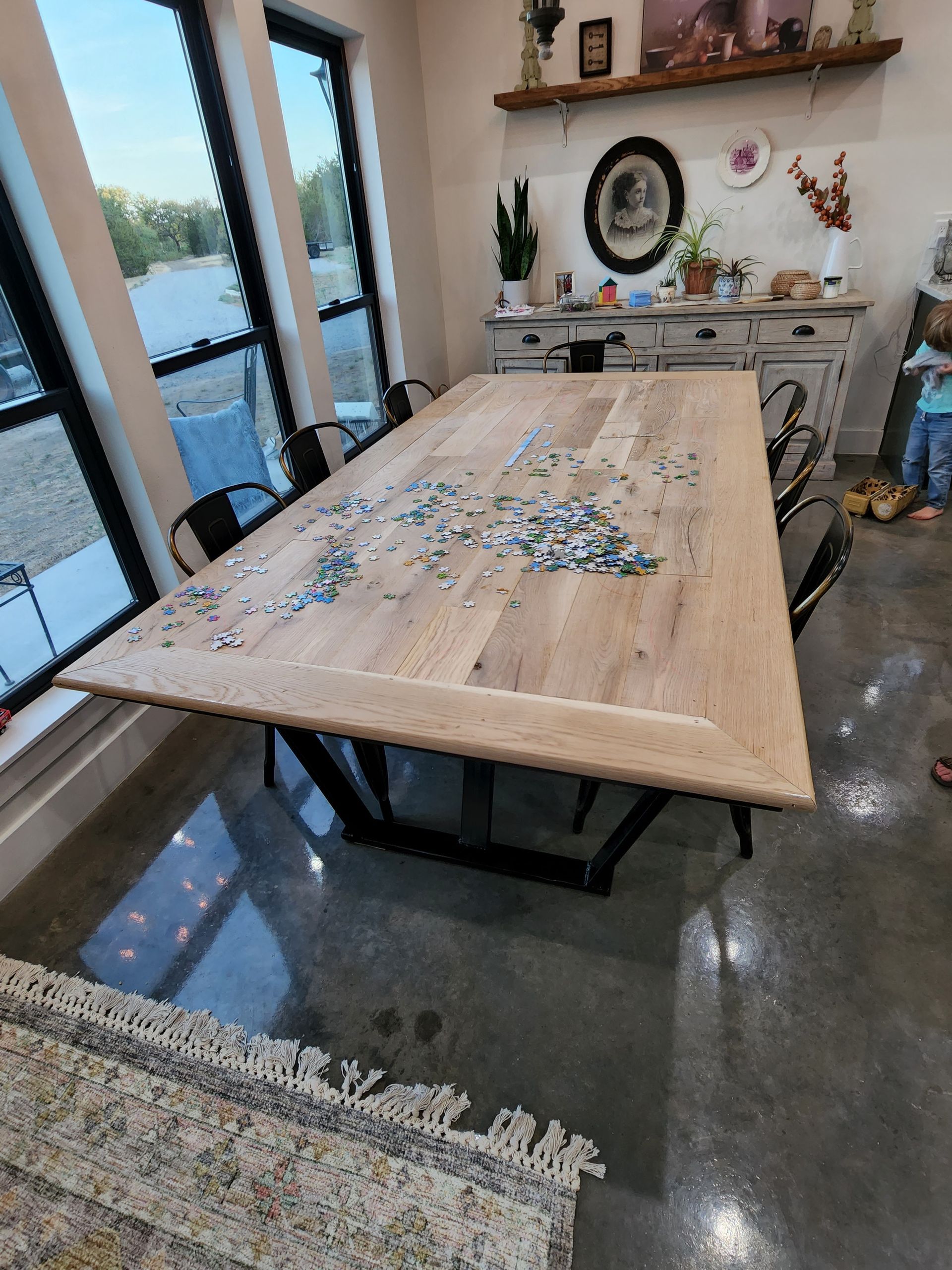 A wooden table with a lot of puzzle pieces on it in a room.