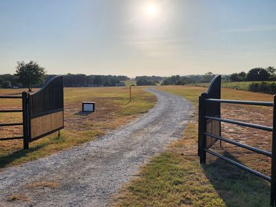 A dirt road going through a field with a fence