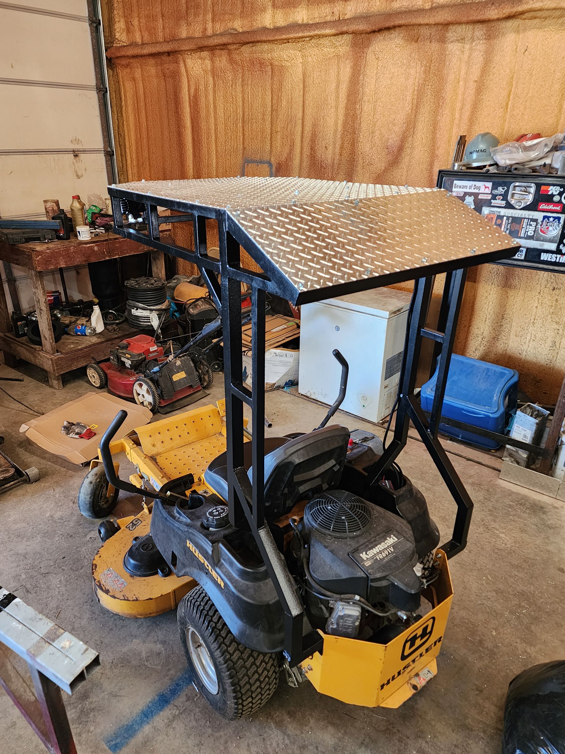 A yellow and black lawn mower with a canopy is parked in a garage.