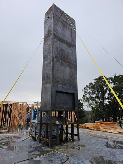 A large concrete structure is being lifted by a forklift