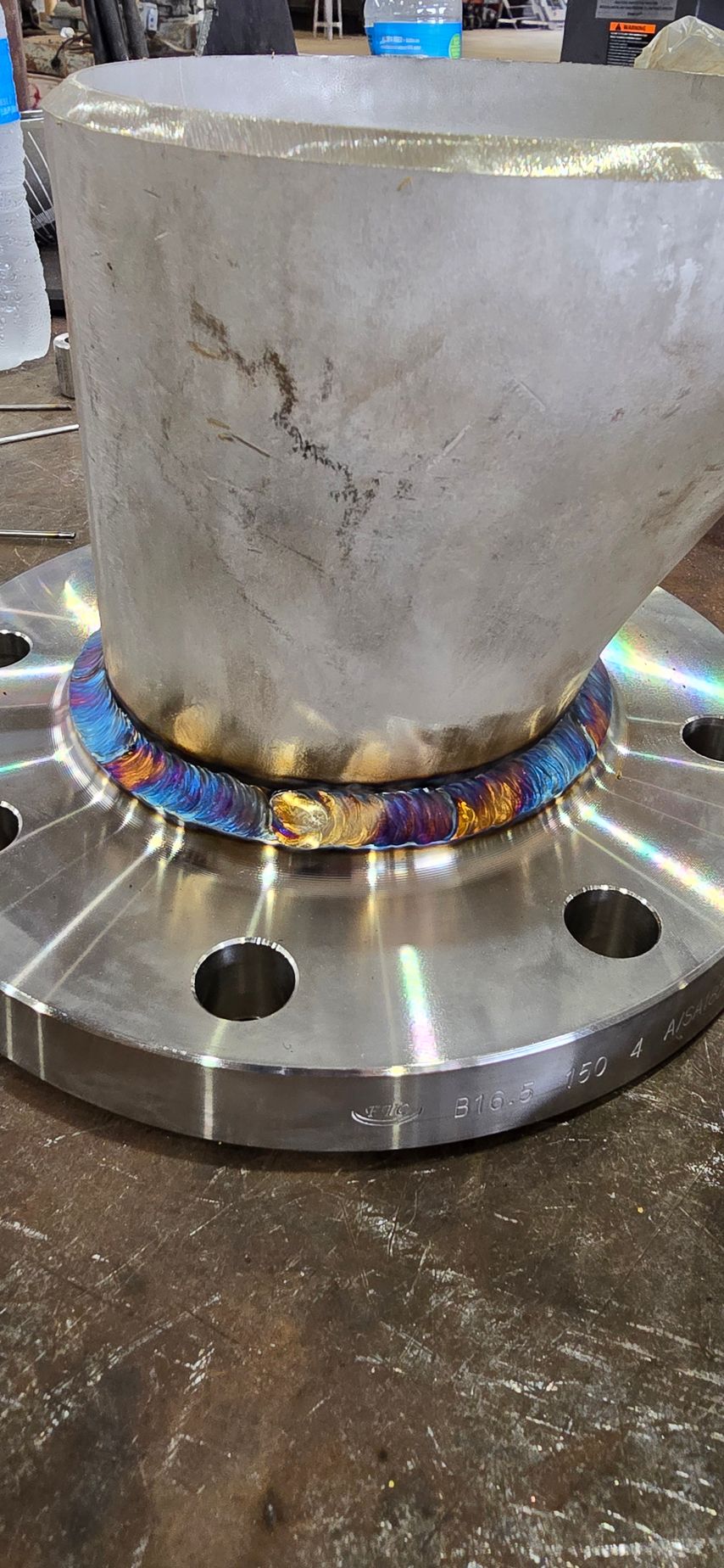 A metal pipe is sitting on top of a metal flange on a table.