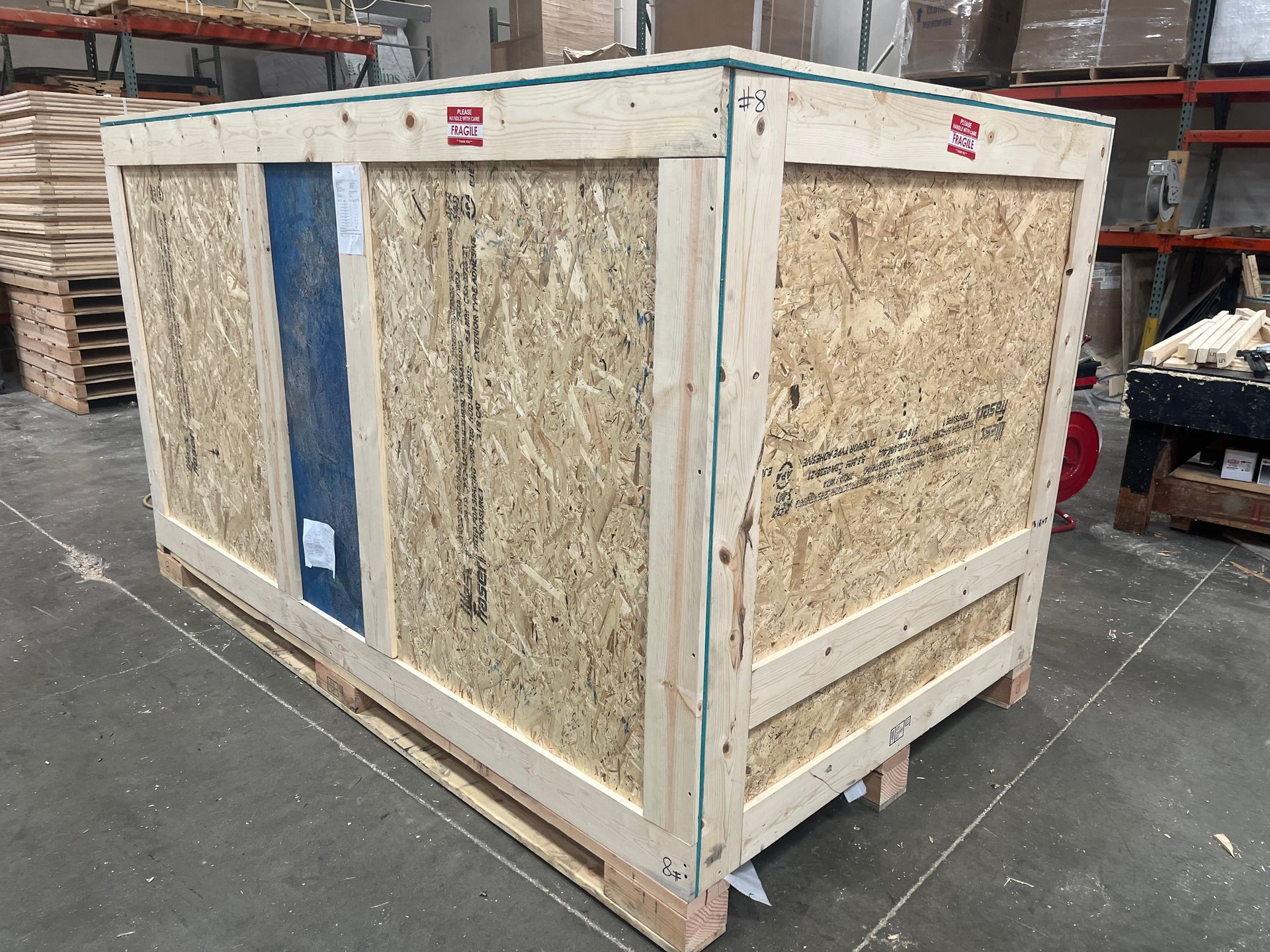 Wooden shipping crate. Light wood construction with open sides, in a warehouse setting.