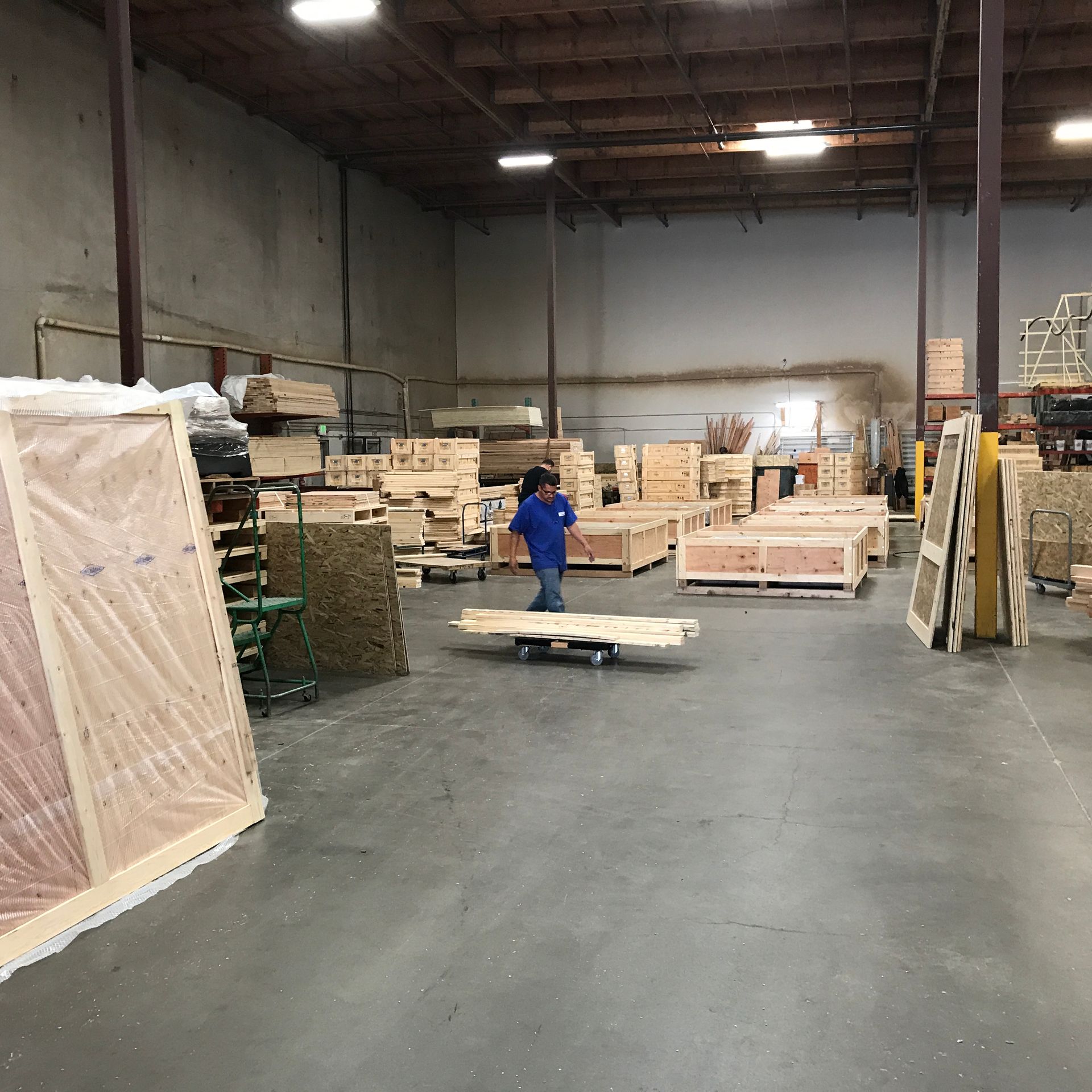 Warehouse workers moving a large crate with rigging, surrounded by other packed crates.