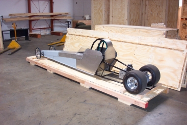 Drag racing car on a wooden pallet in a storage facility.