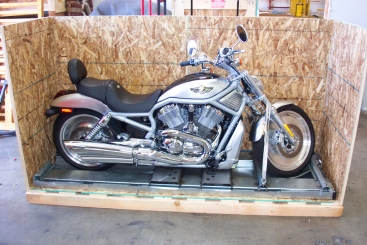 Motorcycle secured inside a wooden shipping crate, ready for transport.