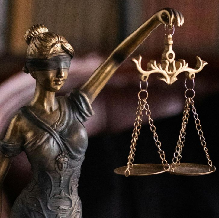 Statue of Lady Justice with blindfold, holding scales, gold and bronze tones.