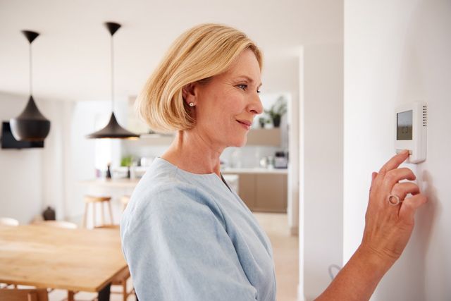 Woman Adjusting Heating Temperature At Home
