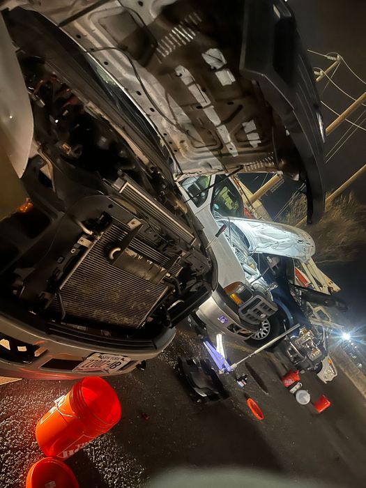 Overturned white truck after an accident, orange bucket on the ground, nighttime scene.