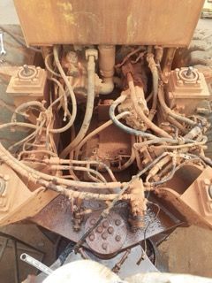 Close-up of weathered machinery with various tubes and parts. Brown and tan colors dominate.