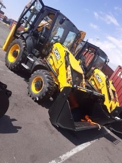 Two yellow JCB backhoe loaders in a parking lot.