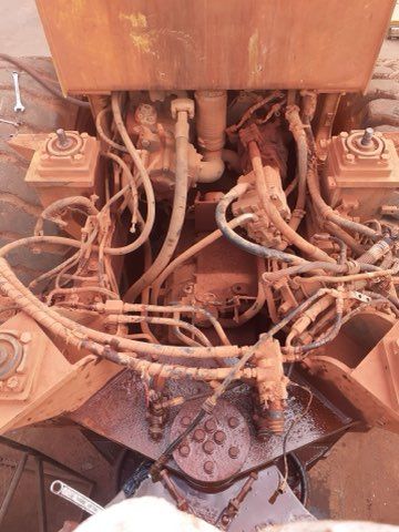 Overhead view of a rusty, complex industrial machine interior with various tubes, hoses, and mechanical components.