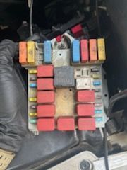 Fuse box with various colored fuses in an engine compartment.