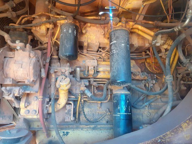 Close-up of a weathered, yellow industrial engine with various pipes, filters, and wires.