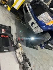 Blue truck with detached steering parts in a garage, next to a black 