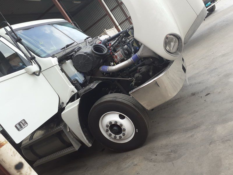 White truck with hood open, showing engine.