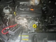 Car engine bay with a jump starter connected; tools are visible.