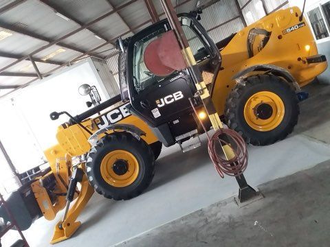 Yellow JCB telehandler in a garage.