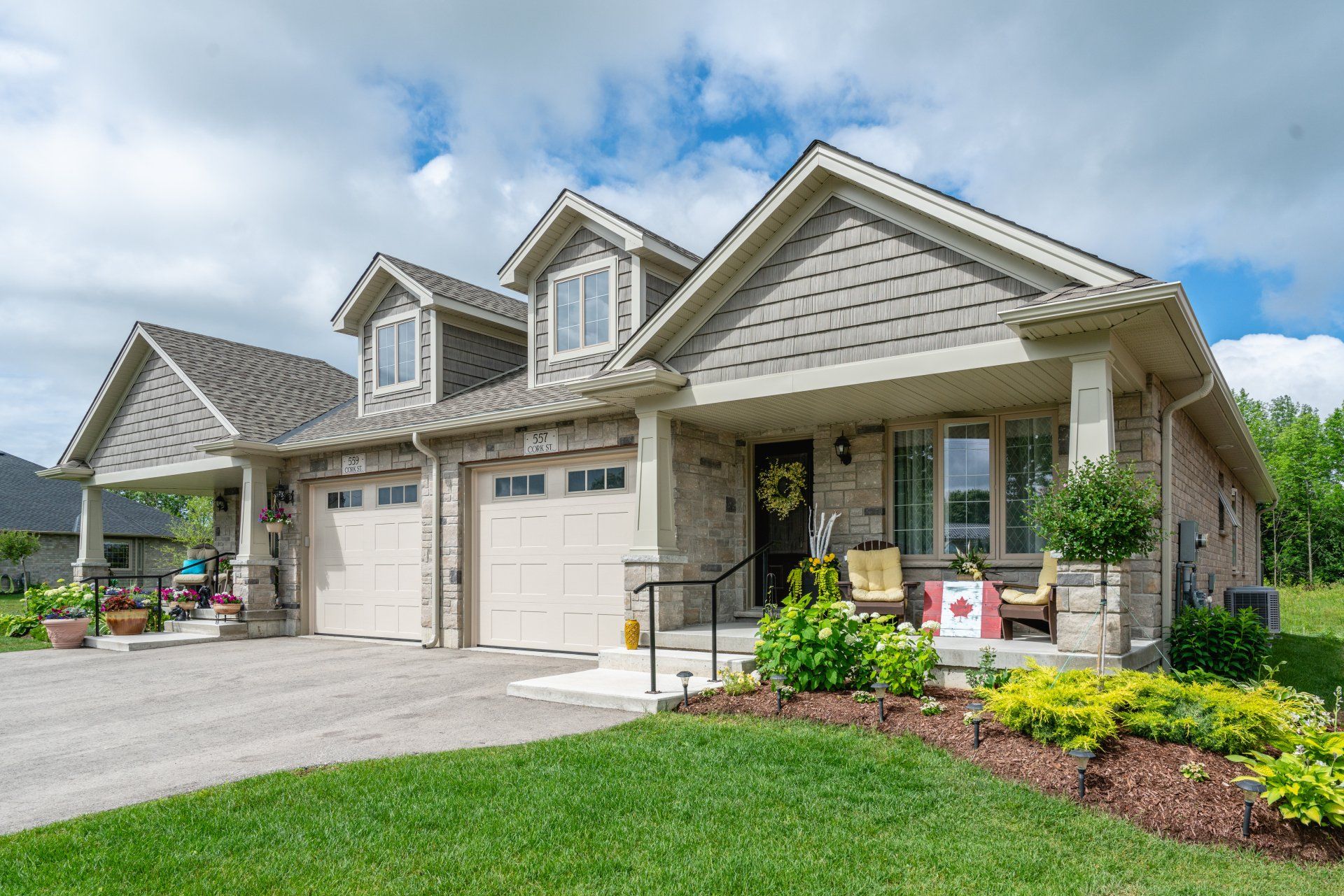 A large house with two garages and a porch on a sunny day.