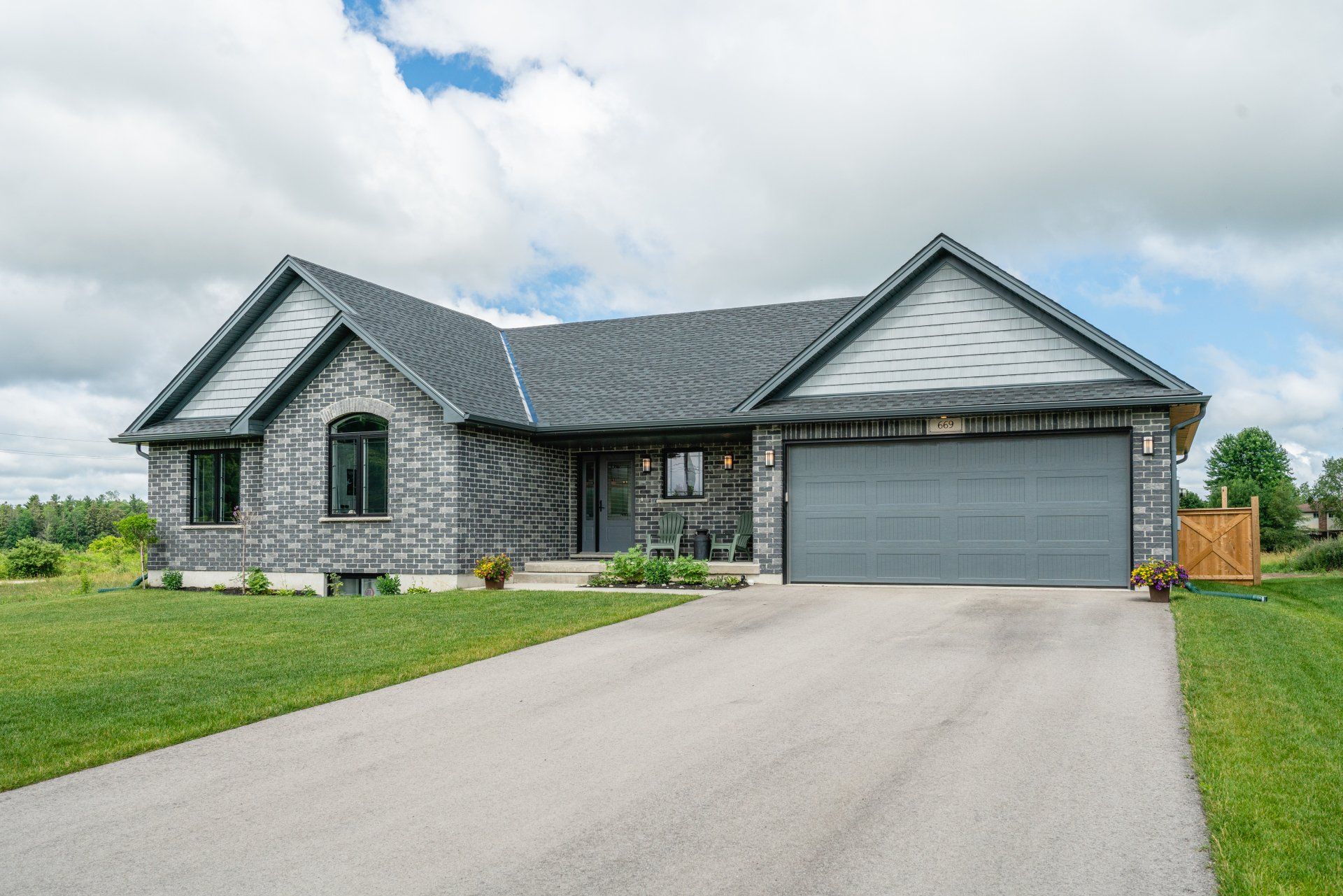 A large brick house with a gray garage door is for sale.