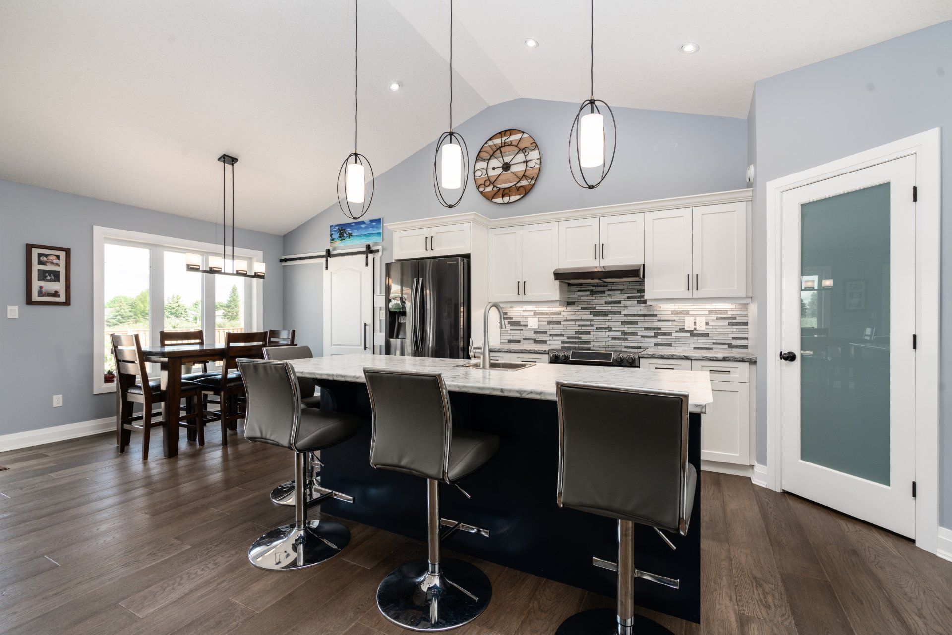 A kitchen with a large island and stools and a dining room in the background.