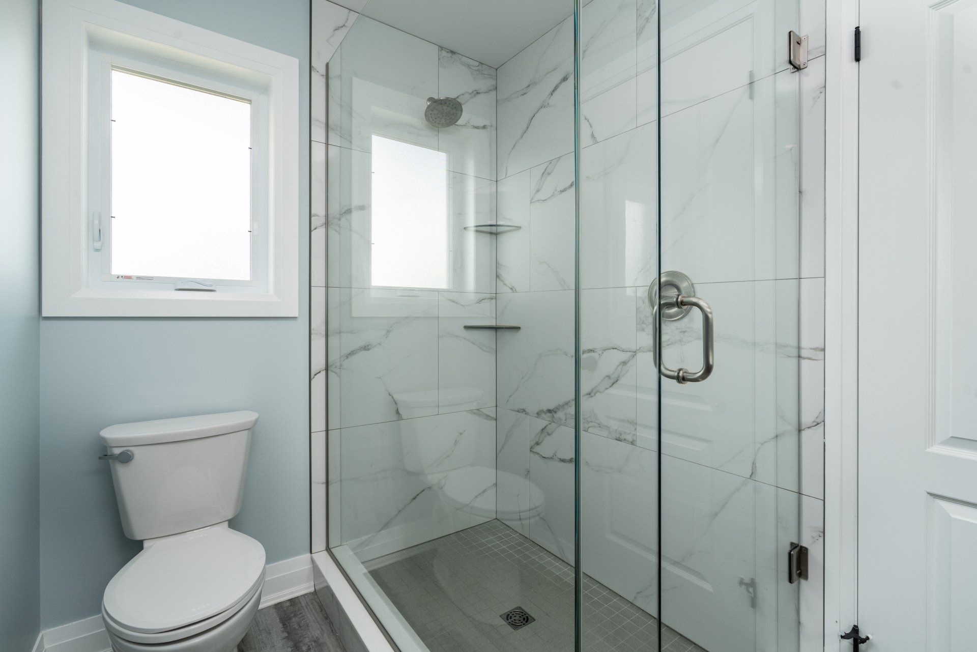 A bathroom with a toilet and a walk in shower with a glass door.