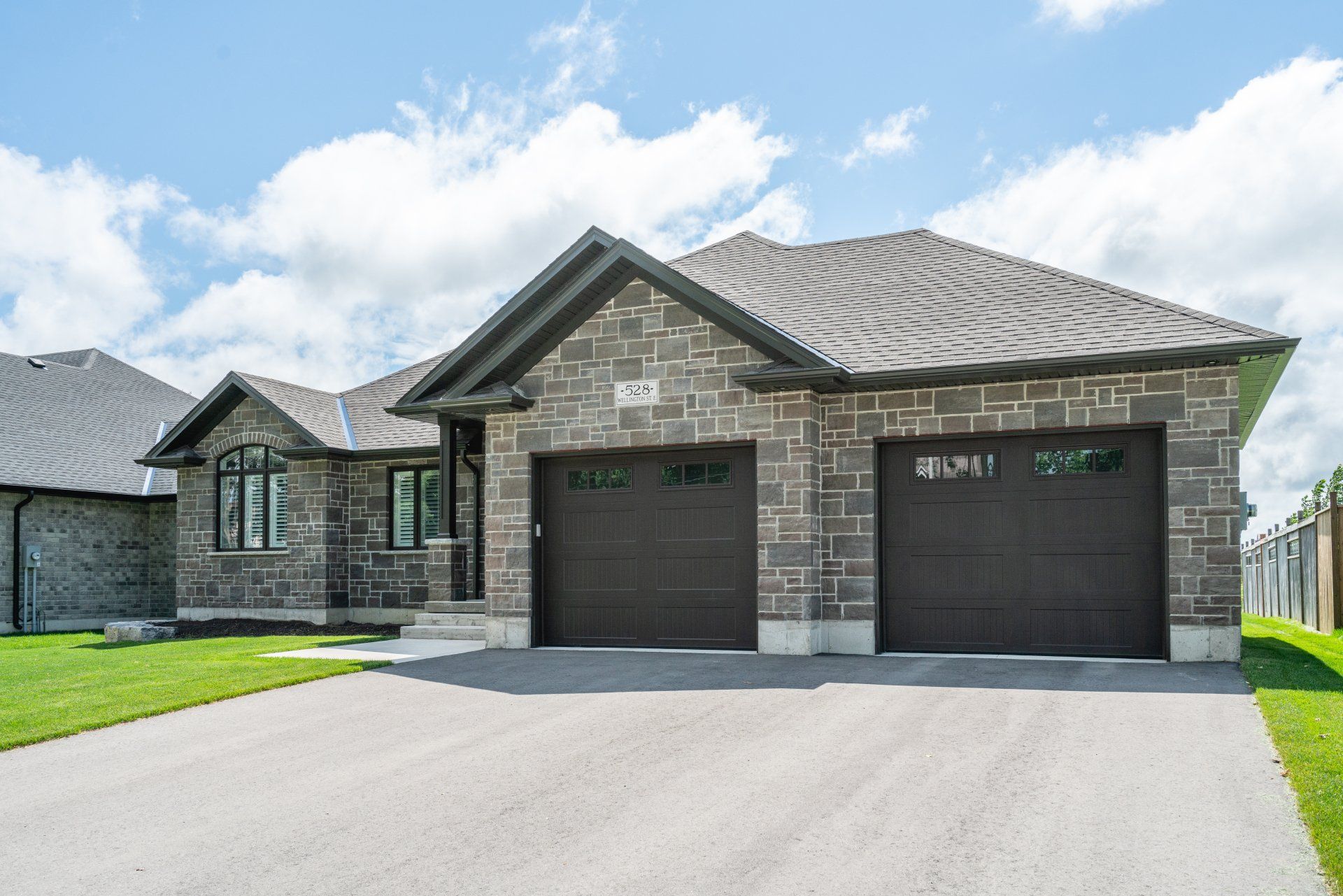 A large brick house with two garage doors and a driveway.