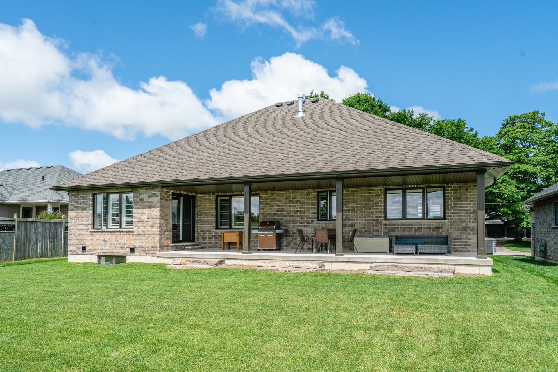 The back of a brick house with a large lawn in front of it.