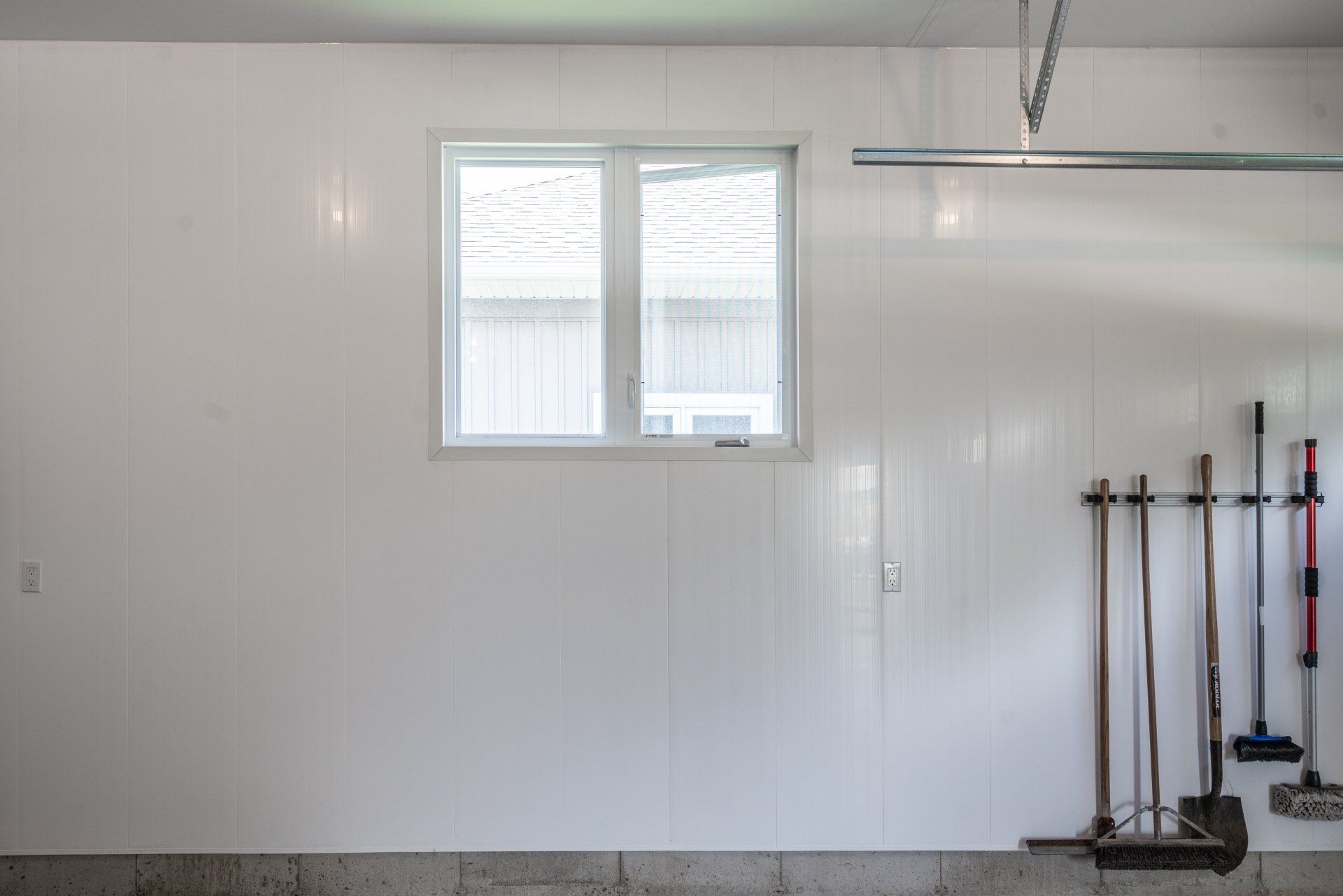A garage with a window and a bunch of tools hanging on the wall.